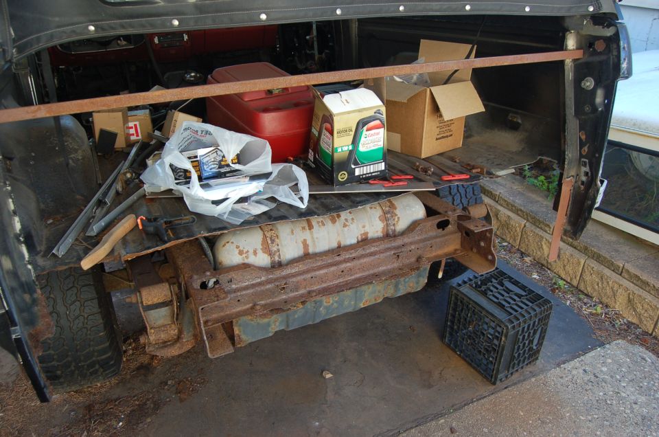 Rear cargo area of a vehicle filled with items including a gas can and oil bottles