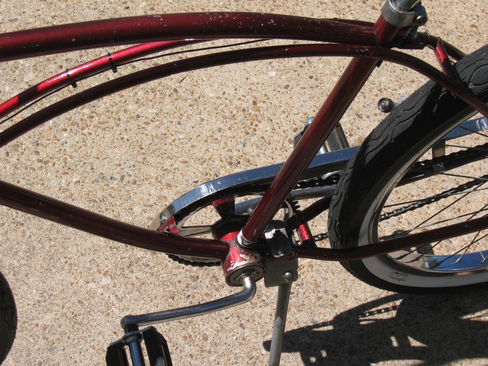 Close-up of a red bicycle frame, showing the crankset, chain, and rear wheel