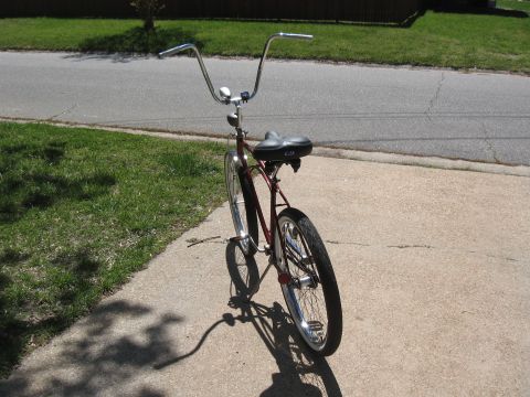 1994 Ford Bronco - A red cruiser bicycle with tall ape handlebars and a black seat is parked on a concrete driveway.
