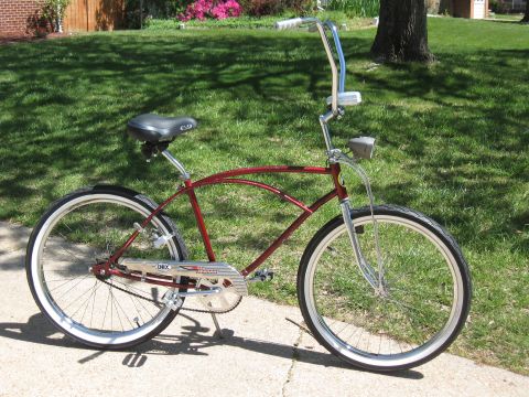 1994 Ford Bronco - A classic red cruiser bicycle with whitewall tires sits on a paved surface in front of a grassy lawn.