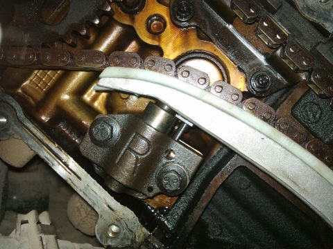 1998 Ford Crown Victoria - Close-up of an engine's timing chain and tensioner mechanism, showing internal components.