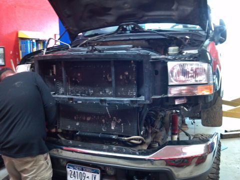 1993 Ford F-150 - Mechanic working on the front end of a Ford truck, with the grille and hood removed for repairs.