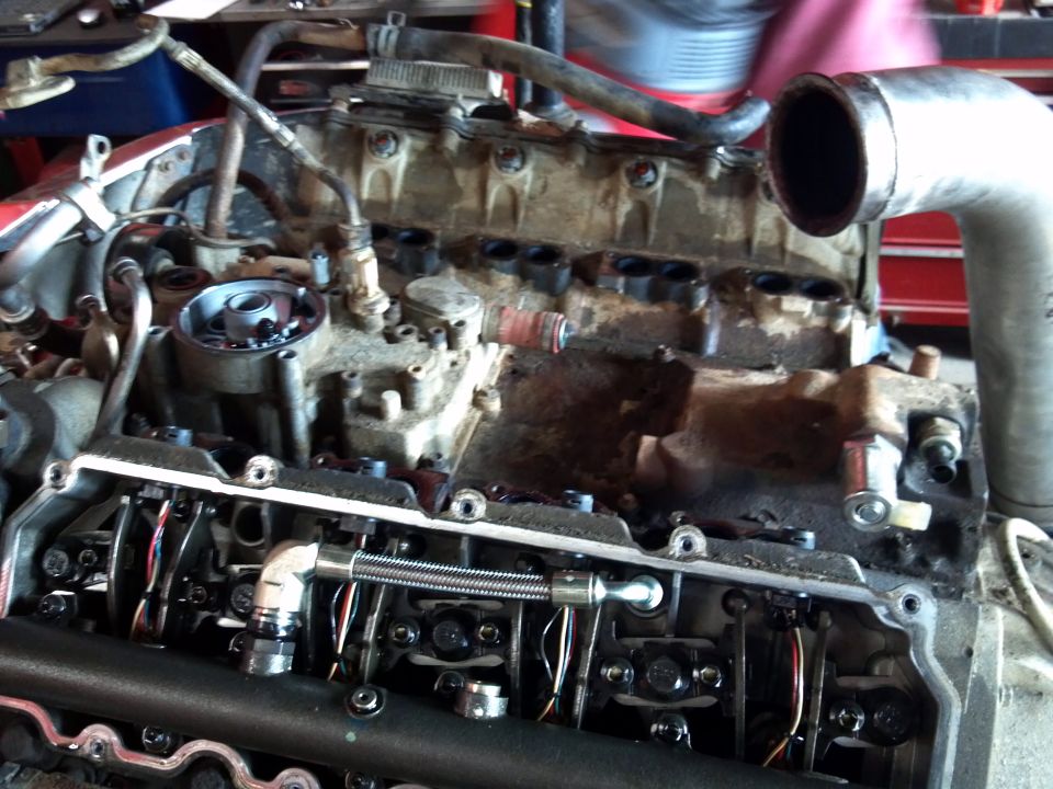 Engine block with valve train exposed, showing lifters and pushrods. Dirty, metallic components