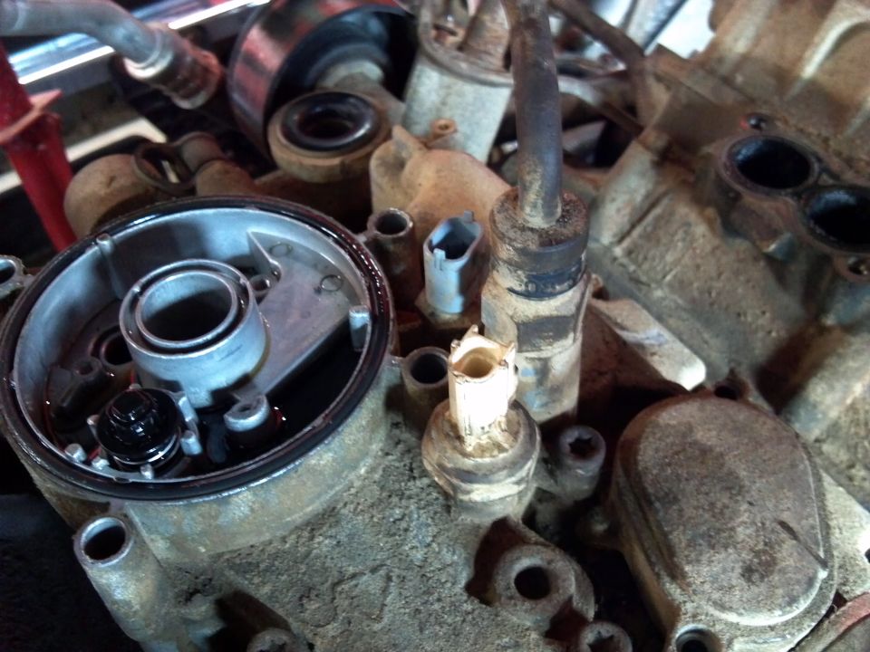 Close-up of an engine's oil filter housing with some oil visible