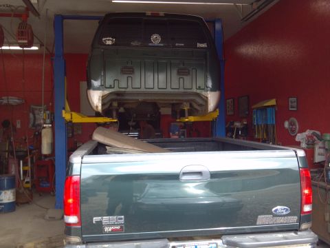 1993 Ford F-150 - A Ford F-250 Super Duty is parked in a garage, with another vehicle being worked on above it.