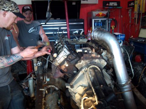 1993 Ford F-150 - Mechanics work on a large engine in a cluttered garage setting.