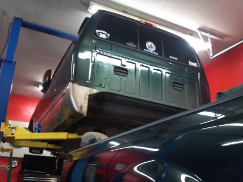 1993 Ford F-150 - Rear view of a green pickup truck being worked on in a garage, with another vehicle visible underneath.