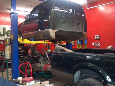 1993 Ford F-150 - Ford Super Duty truck undergoing repairs on a lift, with another truck nearby.