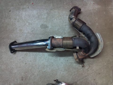 1993 Ford F-150 - This exhaust pipe assembly features a chrome tip and a flexible pipe section, resting on a concrete surface.