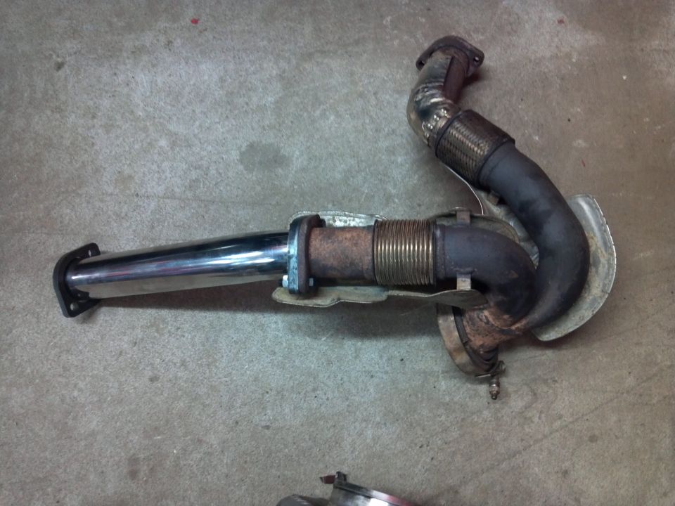 Exhaust pipe assembly with flex pipe and chrome tip, sitting on concrete floor