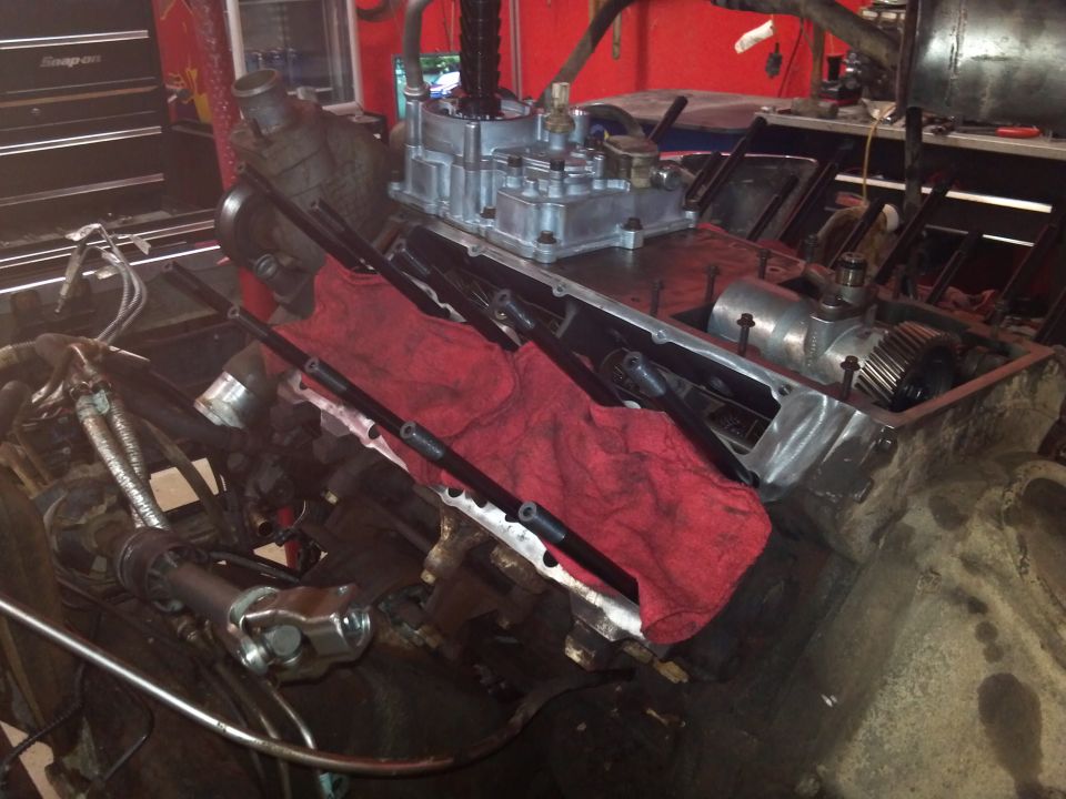Engine block with carburetor and red rags, in a workshop