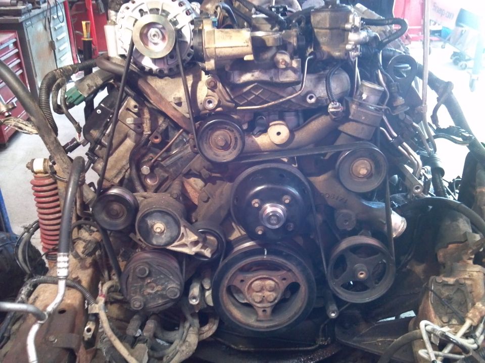 Engine assembly with belts and pulleys, showing alternator and AC compressor