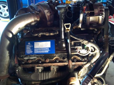 1993 Ford F-150 - Close-up view of an engine assembly a turbocharger and a prominent blue sticker with text.