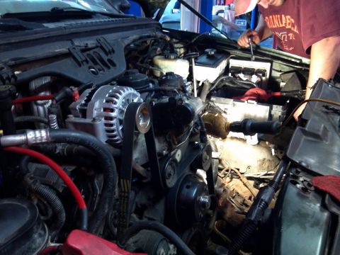 1993 Ford F-150 - Mechanic works on the engine of a truck, focusing on the alternator and belt system.