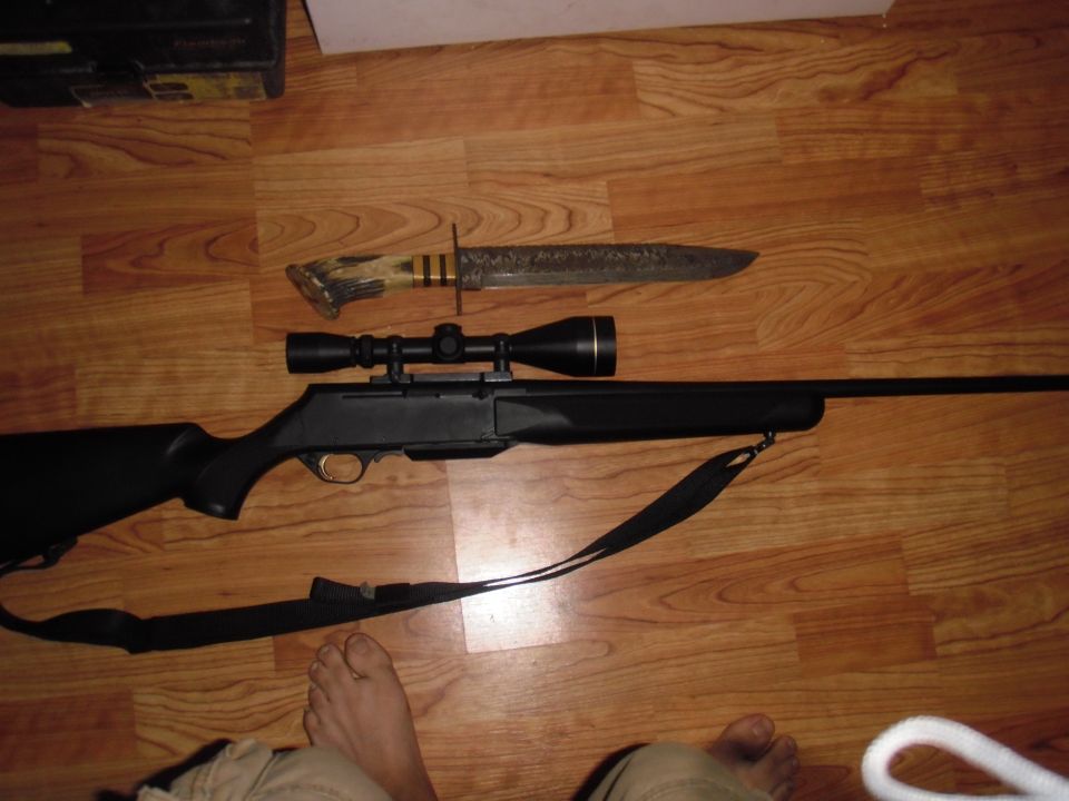 Rifle with scope and hunting knife on wooden floor