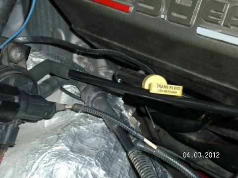 1996 Ford Bronco - Close-up of an engine bay showing a transmission fluid dipstick with instructions to use Mercon fluid.