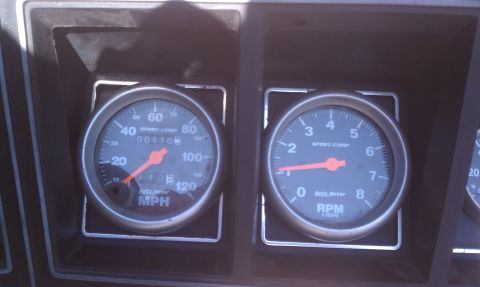 1978 Ford Bronco - Close-up of aftermarket AutoMeter gauges, including a speedometer and tachometer, installed in a vehicle's dashboard.