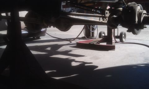 1978 Ford Bronco - The underside of a vehicle is raised on jack stands, revealing its drivetrain and suspension parts.