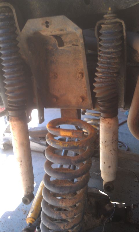 1978 Ford Bronco - Close-up of vehicle suspension components, including a coil spring and shock absorbers.
