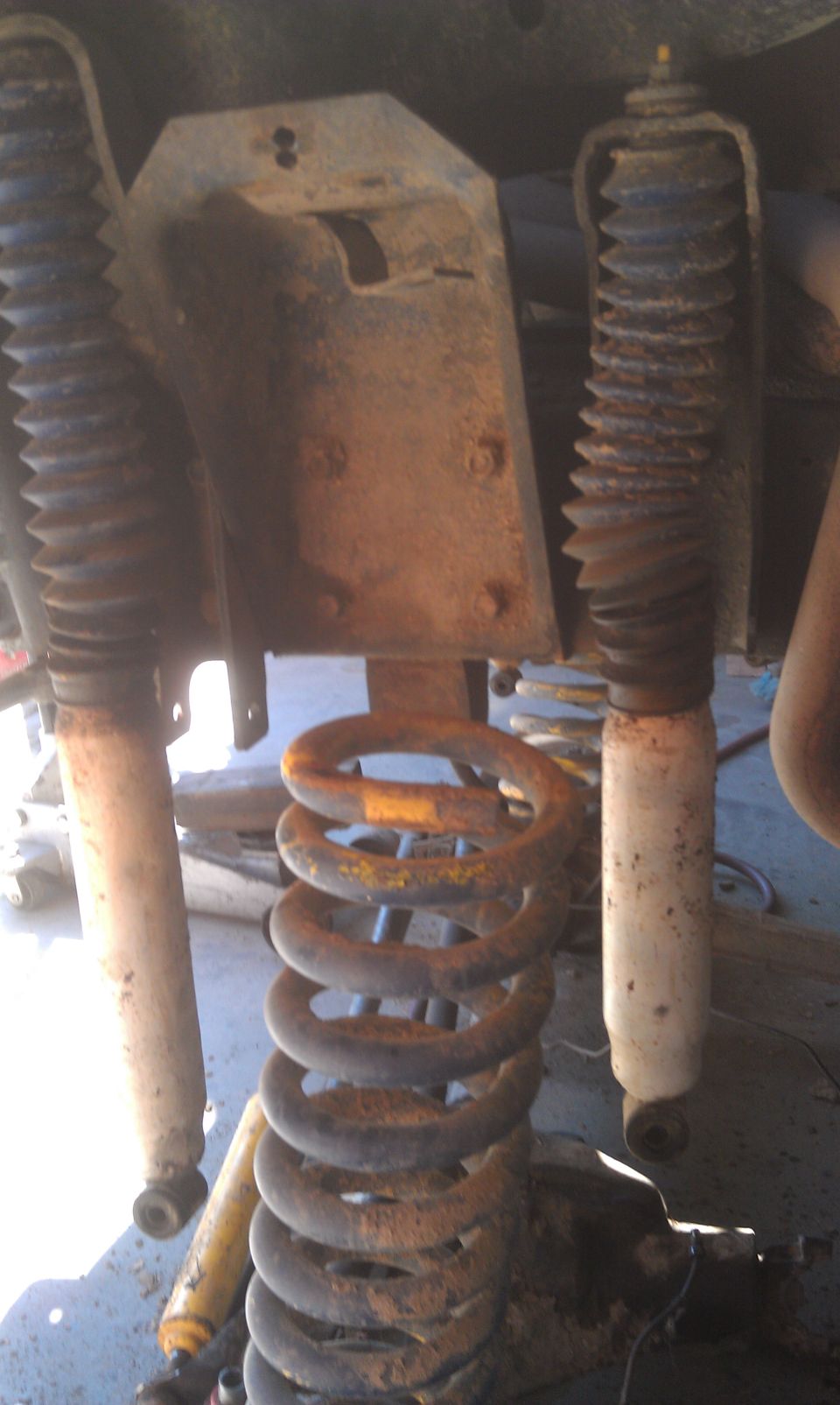 Rusty coil spring and shock absorbers under a vehicle