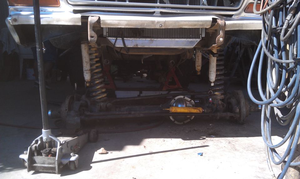 1978 Ford Bronco front axle, suspension, and radiator assembly with a floor jack