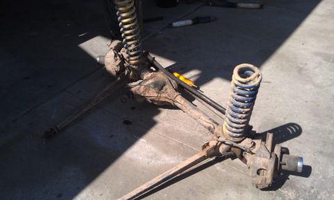 1978 Ford Bronco - This is a close-up view of a vehicle's front axle assembly, including the springs and shock absorbers, resting on the ground.