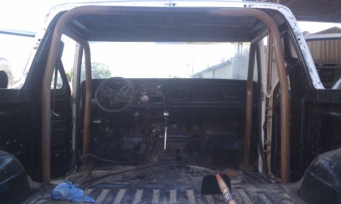 1978 Ford Bronco - The interior of a 1978 Ford Bronco is visible, a custom-installed roll cage and a bare cargo area.
