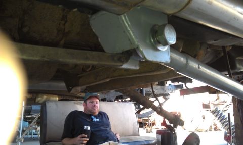 1978 Ford Bronco - A person relaxes on a couch while underneath a vehicle, likely during a repair or modification.