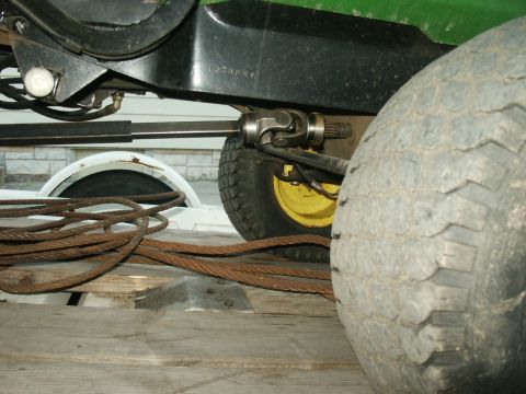 1966 Ford Bronco - Detail of a tractor's drivetrain and tire, with heavy cables coiled nearby.