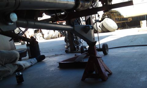 1978 Ford Bronco - A vehicle's undercarriage is visible, supported by jack stands, with a stack of tires in the background.