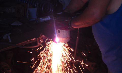 1978 Ford Bronco - Sparks fly as metal is cut with a torch in a workshop setting.