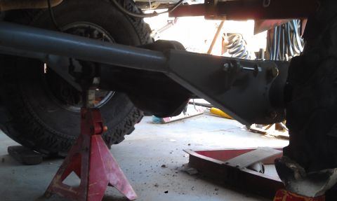 1978 Ford Bronco - Vehicle axle and suspension parts are shown, supported by red jack stands in a workshop setting.
