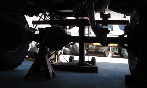 1978 Ford Bronco - The underside of a vehicle is shown, focusing on the rear axle and differential assembly. It is elevated on jack stands for maintenance.