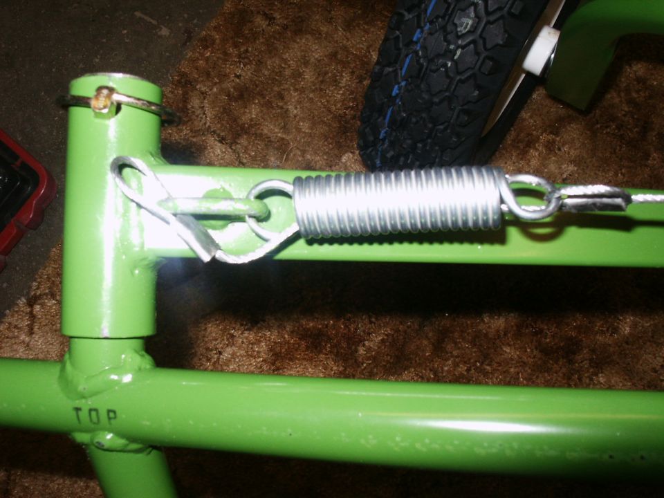 Green metal frame with spring, pin, and tire visible