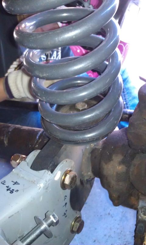 1978 Ford Bronco - A close-up view of a vehicle's suspension system, focusing on a coil spring and its mounting bracket.