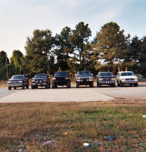 1988 Ford Bronco - A lineup of six Ford Broncos, likely from the early to mid-1990s, are parked side-by-side.