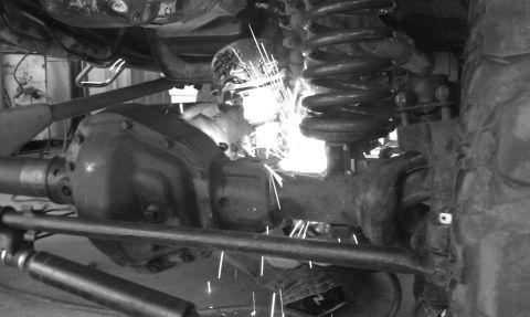 1978 Ford Bronco - Welding is performed on the rear axle assembly of a vehicle, with sparks visible.