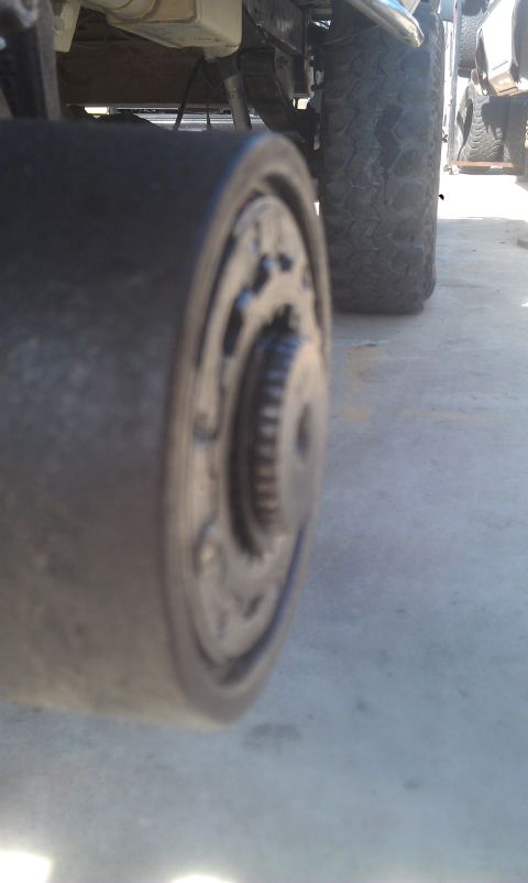 1978 Ford Bronco - A close-up view of a vehicle's axle hub and tire, with another vehicle partially visible in the background.