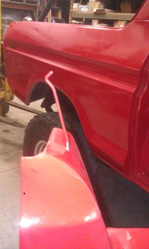 1978 Ford Bronco - Close-up side view of a red 1978 Ford Bronco half door, with a red gas can positioned in front of the rear fender.