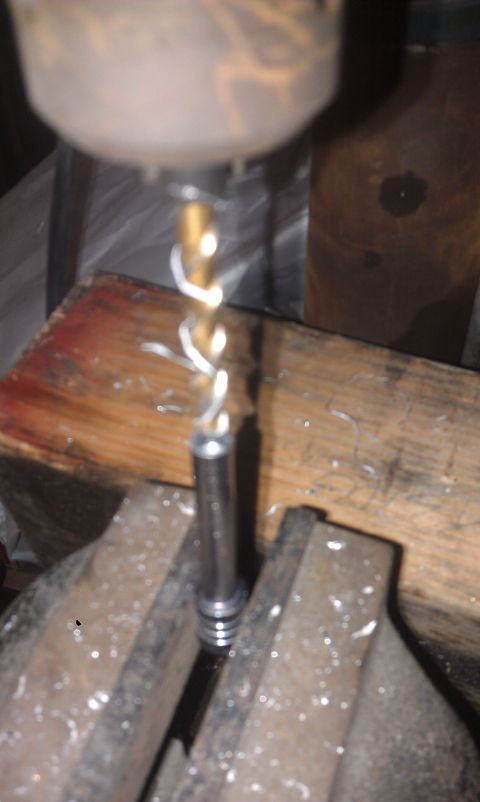 1978 Ford Bronco - A drill press is used to work on a metal component secured in a vise.