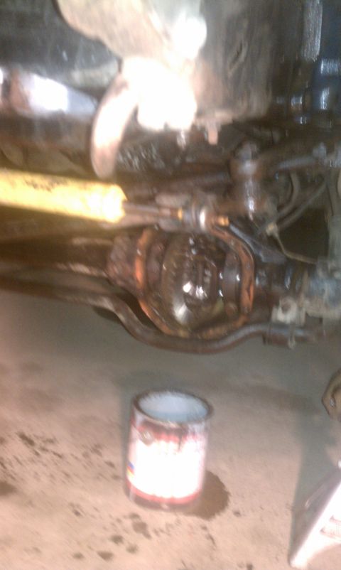 1978 Ford Bronco - Underside view of vehicle suspension and differential components with a can on the floor.