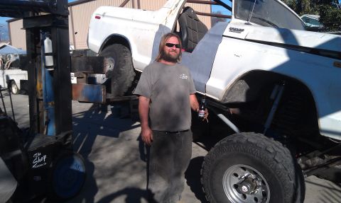 1978 Ford Bronco - Man poses with a heavily modified 1978 Ford Bronco, likely undergoing restoration or customization.