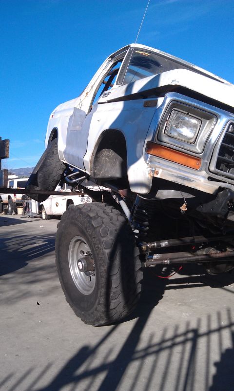 1978 Ford Bronco - A heavily modified truck is shown with its front wheel lifted high off the ground.