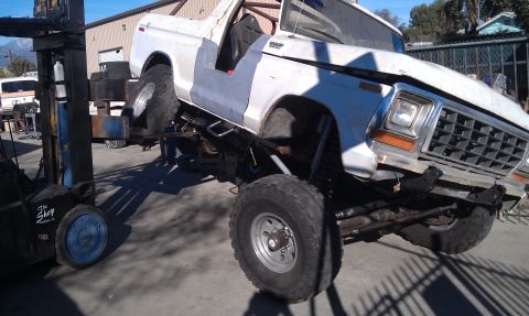 1978 Ford Bronco - This 1978 Ford Bronco is being lifted by a forklift, revealing its custom suspension and off-road tires.