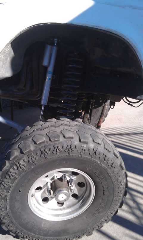 1978 Ford Bronco - The suspension system of a lifted vehicle, large off-road tires and prominent shock absorbers.