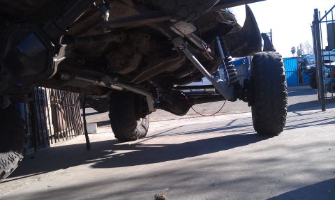 1978 Ford Bronco - The complex suspension and drivetrain components of a heavily modified off-road vehicle are visible from below.
