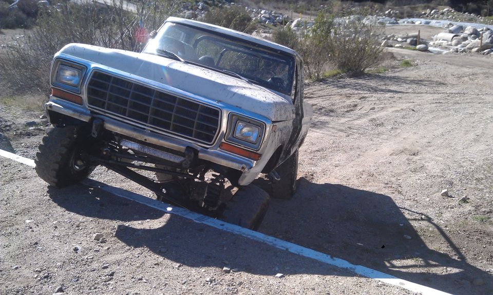 White Ford F-Series truck with lifted suspension on a dirt road