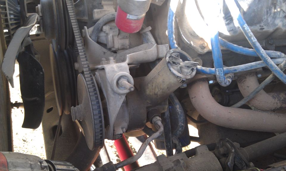 Close-up of engine parts including fan, belts, hoses, and exhaust manifold