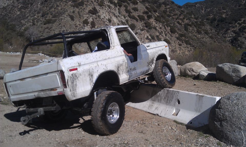 White 1978 Ford Bronco flexing over obstacle