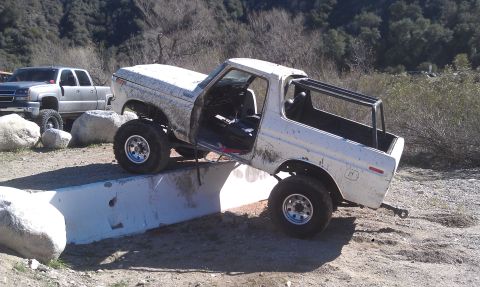 1978 Ford Bronco - An off-road SUV is positioned on a concrete barrier with a roll cage installed in the rear.